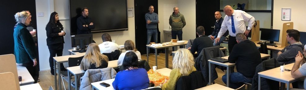 Deelnemers aan een door financial engneering bekostigd leerwerktraject staan en zitten in een klaslokaal.