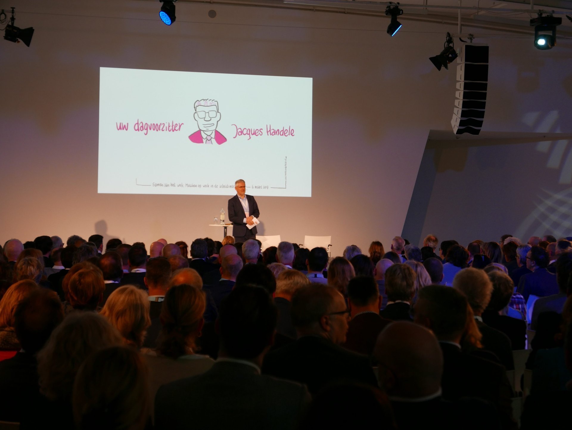 een persoon die op een podium staat met een menigte die toekijkt