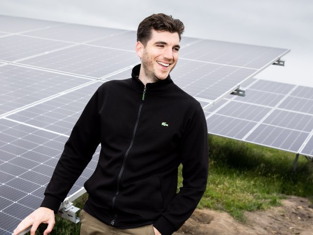 Een zonnepaneleninstallateur staat voor een zonnepanelenveld.