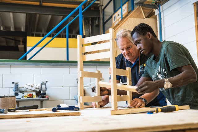 Medewerkers bouwen een houten stoel