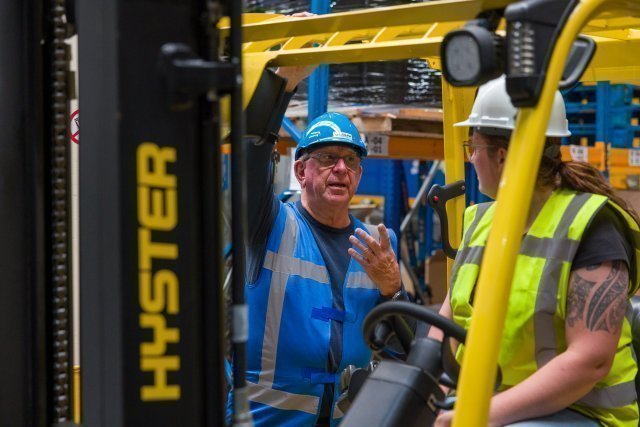 Menso bedrijfbezoek. 2 heftruckmedewerkers in gesprek met elkaar