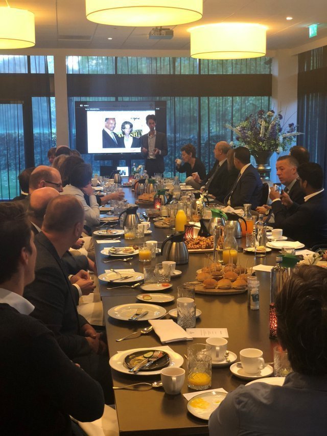 een groep mensen die rond een tafel zitten met eten en drinken