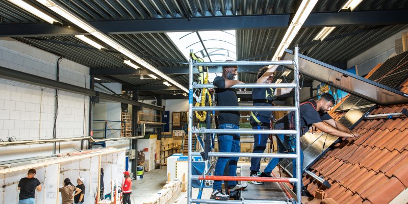 Medewerkers en begeleider monteren zonnepanelen 